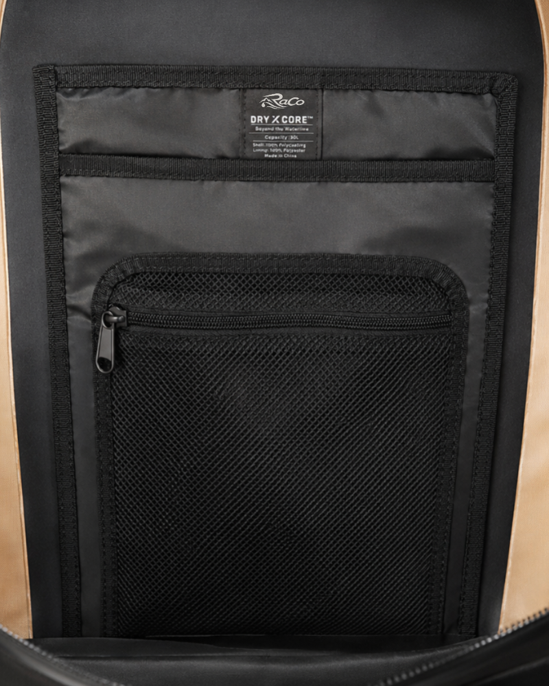 Close-up of the interior of a backpack showing a black mesh zippered pocket and a black fabric organizer panel with a visible Fjørør 'DRY x CORE' label.