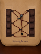 Close-up of a tan tactical pouch or bag with dark brown lacing and webbing straps, featuring the printed brand name 'BEYOND THE WATERLINE' near the bottom.